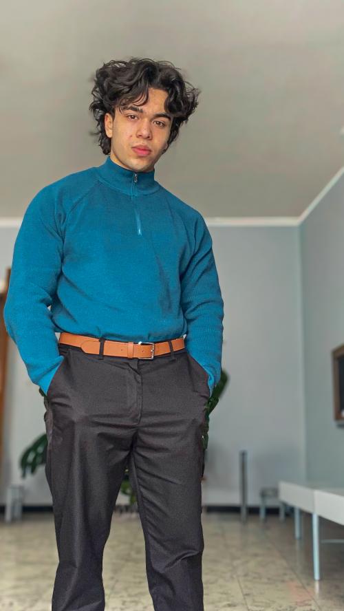 Auteur model Dylan - Portretfoto van mij in een blauwe trui in een woonkamer setting, met een serieuze blik. De foto is genomen door Pete.