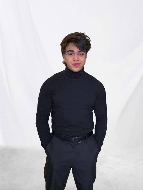 Auteur model Dylan - Portretfoto van mij in een zwarte trui en nette broek voor een witte backdrop. De foto is genomen door Jan.
    Studio 